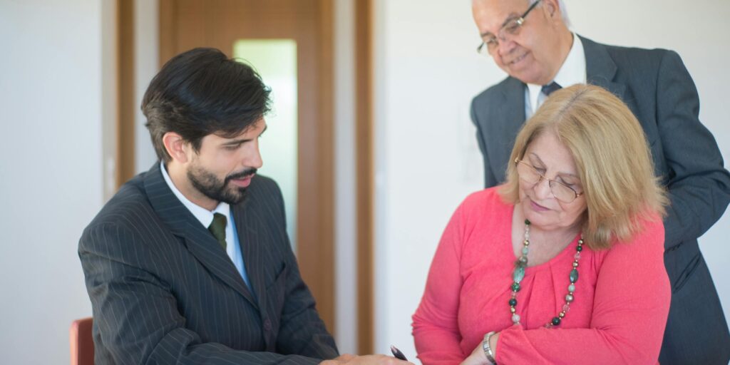 Matrimonio mayor firmando con su abogado los documentos de una propiedad heredada